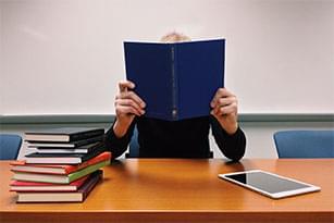 student hiding behind book